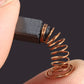 Charbon moteur 5x5x8 mm tenu entre deux doigts, ressort de 16 mm déployé